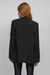 modelo veste blazer preto alongado com ombreiras, bolsos frontais, forro, sem botão, a terceira peça perfeita para seu look