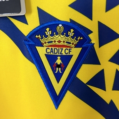 camisa-titular-do-cádiz-elements-retrô-2002-2003-home-1-casa-i-principal-amarela-e-azul-com-patrociníos-patrocinadores-uniforme-antiga-rara-colecionadores-reliquía-velha-antiguidade-coleção-profissional-torcedor-torcedores-elastano-futebol-masc