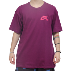 Camiseta Nike SB Mini Logo Roxa. Modelo básico em cor puxada para o roxo. Possui pequeno gráfico único do logo da marca na altura do peito no lado esquerdo. Costas lisas.