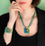 Mujer exhibiendo conjunto de collar y pulsera en tonos verdes, hechos a mano con vidrio y cuero