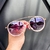 O Óculos de Sol Play Branco possui um design moderno, em formato redondo, detalhes em acetato em volta das lentes na cor branco, armação em metal na cor rose e lentes degradê na cor roxa.