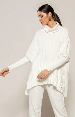 Modelo vestindo blusa oversized off white de algodão com detalhe em gola alta e mangas largas.