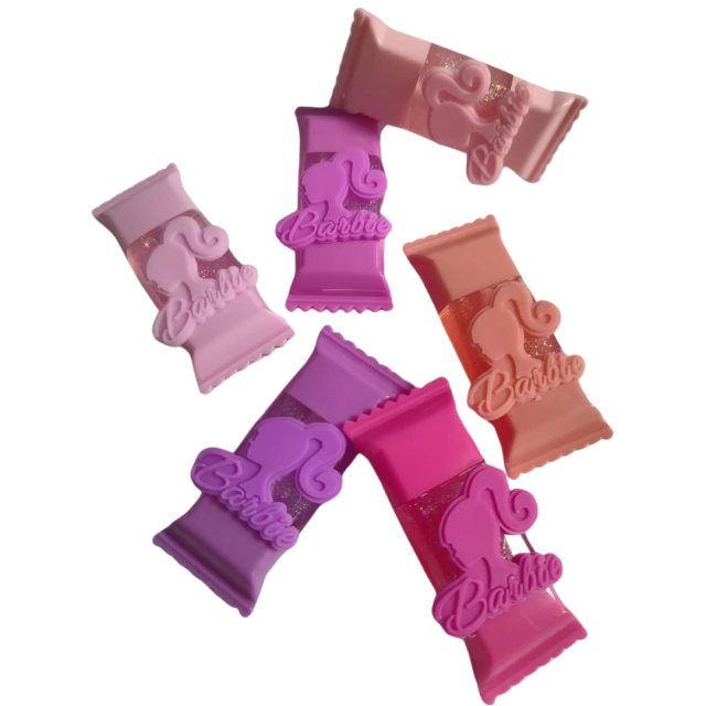 Conjunto de clipes de cabelo em formato de doces, nas cores rosa e lilás, com o logo da Barbie.