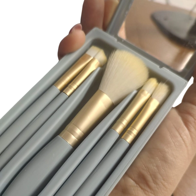 Conjunto de pincéis de maquiagem em estojo compacto, com cabos em tom de azul e detalhes em dourado.
