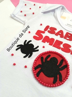 Body de bebê branco com decoração temática do Homem Aranha, para menina com nome e meses em destaque, com aranhas em vermelho e preto e pérolas ideal para festa de mesversario e aniversario