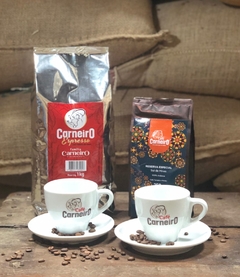 Uma embalagem de Café Carneiro Reserva Especial e Café Espresso Carneiro, junto de duas xícaras Carneiro