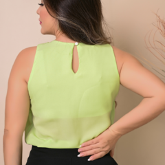 Mulher com blusa verde clara, vista de costas, mostrando detalhe de botão na parte de trás.