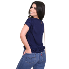 Modelo feminina de costas, usando uma blusa azul escura e jeans, sorrindo.