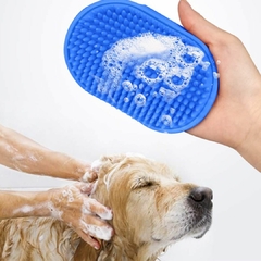 Escova de banho massageadora para pets, em cor azul, sendo utilizada em um cachorro enquanto espuma de shampoo cobre o animal.