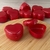 Caixinhas acrílicas pequenas em formato de coração na cor vermelha sob tábua de madeira