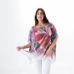 Blusa Sublime con estampado de hojas en tonos cálidos, usada por una mujer que sostiene la prenda.