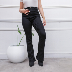 Pantalones de jean negro de corte semi oxford, con una mujer posando y una planta en una maceta blanca al fondo.