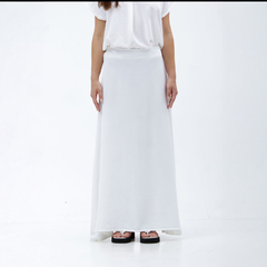 Falda maxi blanca Nalami, con un diseño elegante y fluido, combinada con una blusa blanca y sandalias negras.