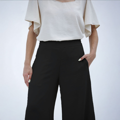 Pantalones palazzo negros con una blusa clara, mostrando un diseño moderno y cómodo.