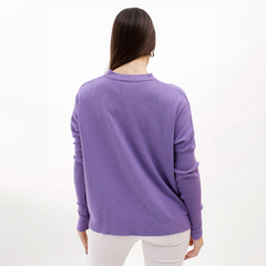 Mujer de espaldas usando un sweater morado, con detalles en las mangas, en un fondo blanco.