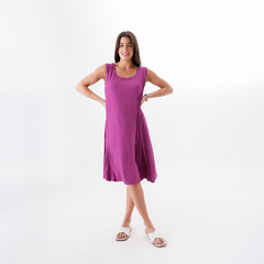 Mujer posando con un vestido morado sin mangas, en un fondo blanco.