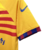 Quarta camisa Barcelona Nike 2023-2024 masculina em amarelo vibrante, listras vermelhas ousadas e toques de azul. Inspirada na braçadeira de capitão de Sergio Busquets, gola redonda amarela, punhos blaugrana e Swoosh da Nike em azul escuro.