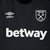 Camisa reserva West Ham Umbro 2022/23 em preto, rosa e azul, inspirada na rampa de lançamento da Thames Ironworks. Escudo Hammers, logo Umbro e detalhes em destaque.