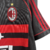 Terceira Camisa Retrô do AC Milan Adidas 1998-1999. A camisa é listrada em preto e vermelho com o escudo do Milan bordado no lado esquerdo do peito e o logotipo da Adidas no lado direito. As mangas são curtas e pretas com listras finas vermelhas. A gola é