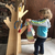 niño colgando su abrigo en el perchero de madera en forma de árbol
