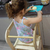niña usando la torre de aprendizaje como silla alta para trabajar sobre una mesada