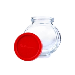 um pote de vidro para guardar temperos e condimentos aberto ao lado da sua tampa vermelha de plástico