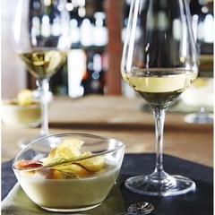 uma taça de vidro com sobremesa e uma taça de vinho branco do lado