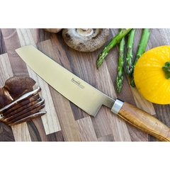 uma faca alemã, da marca nesmuk, com lâmina de aço inox com nióbio em cima de uma tábua com legumes