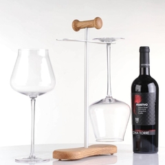 Uma taça de vinho em um suporte e uma garrafa de vinho com outra taça ao lado 