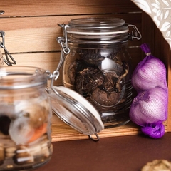 um pote de vidro hermético fechado com alimento dentro de um armário e cebolas roxas do lado