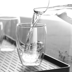 um copo de vidro de parede dupla enchendo de água em um ambiente elegante