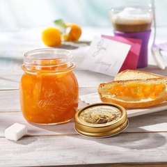 Um pote de vidro aberto de geleia de laranja ao lado de um sanduíche