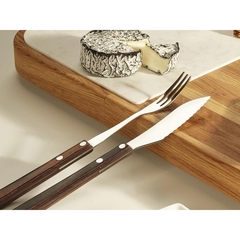 um garfo e uma faca para queijos, apoiados em uma tábua com um queijo