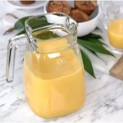 uma jarra de vidro com suco de laranja sobre uma mesa posta