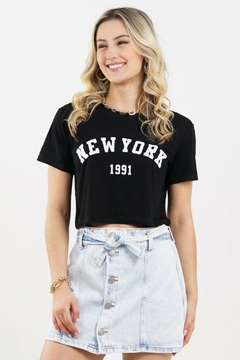 Modelo loira usando um cropped preto com estampa "New York 1991". Posando sobre um fundo branco. G&B Bros!