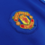 Logotipo bordado do Manchester United em uma camisa azul de manga longa.