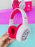 Fones de ouvido Bluetooth sem fio Hello Kitty com design colorido e detalhes em rosa, sendo segurados por uma mão.