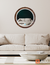 Round LED mirror with a luminous oak frame, reflecting a modern living room setting.