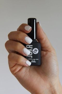 Una mano con las uñas pintadas sostiene el esmalte de uñas semipermanente, de nombre 00 Ultra White, de la marca Juka, color Blanco puro.