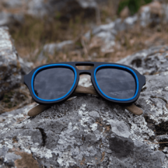 anteojos de sol de madera (patillas) y frente de acetato negro con aro incrustado color azul, con lentes grises modelo Hanoli BOLD estilo aviador marca Nómade