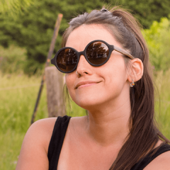mujer luciendo anteojos de sol de madera (patillas) y acetato negro (frente) con lentes polarizados modelo Viena. Marca Nómade