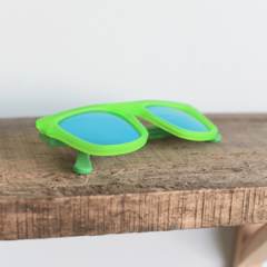 anteojos de sol de acetato coloverde brillante mate con lentes espejados polarizados color azul modelo Tulum PA marca Nómade sobre fondo de madera