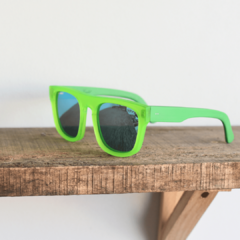 anteojos de sol de acetato coloverde brillante mate con lentes espejados polarizados color azul modelo Tulum PA marca Nómade sobre fondo de madera