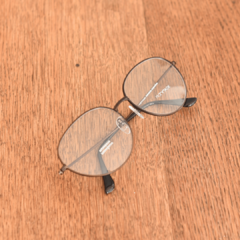 anteojos de metal color cobre de forma redonda con puente bajo modelo Los Pioneros marca Nómade sobre mesa de madera vista cenital