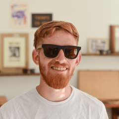 hombre joven de piel blanca y pelo rojo con anteojos de sol estilo wayfarer de acetato color negro con patillas de madera modelo Mykonos marca Nomade