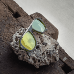 anteojos de sol estilo aviador de acetato color verde oliva traslucido con lentes espejados color bronce modelo patagonia pa marca nomade sobre fondo de piedra