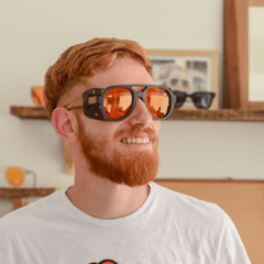 hombre joven de piel blanca y pelo rojo con anteojos de sol de estilo aviador de acetato color negro con apliques laterales de cuero marron y lentes color ambar modelo roma adv marca Nomade