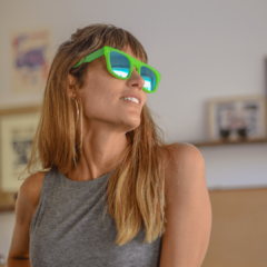 mujer joven con pelo largo rubio con flequillo con anteojos de sol de estilo rectangular color verde fluo con lentes espejados color azul modelo Tulum PA marca Nomade