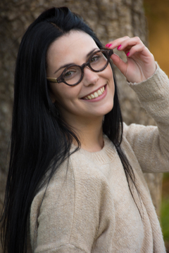 Mujer con anteojos de madera (patillas) y acetato (frente) color tipo nacar de forma redondeada para colocar lentes de aumento modelo Liverpool marca Nómade