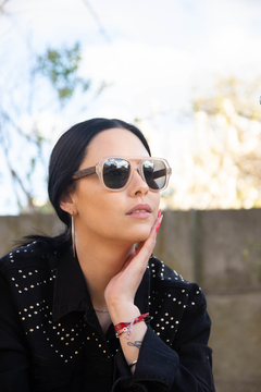 Mujer con anteojos de madera (patillas) y acetato (frente) color rosa traslúcido tipo aviador con lentes de sol polarizados modelo Barker marca Nómade (vista de costado)